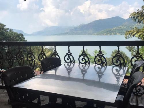 a table on a balcony with a view of the water at The Green Gate Resort Mulshi in Pune