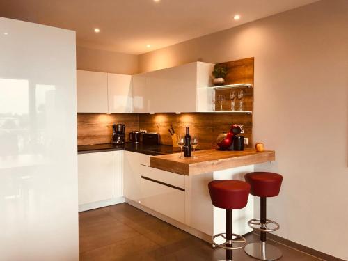 a kitchen with white cabinets and red bar stools at Penthouse Apartment mit Alpenblick in Friedrichshafen