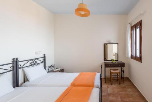a bedroom with a bed and a desk with a mirror at Asterias House in Donoussa