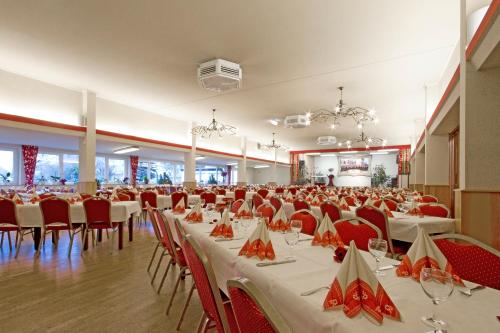 a banquet hall with white tables and red chairs at Hotel Mennicken in Würselen