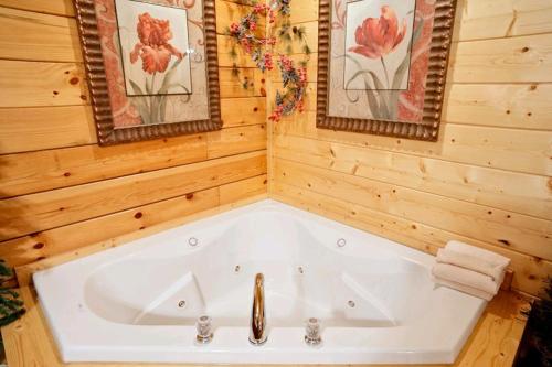 een wit bad in een houten badkamer met 2 foto's bij Call Of The Wild in Sevierville