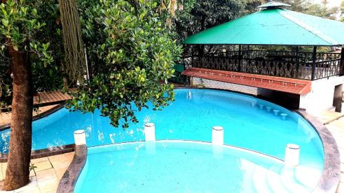 a large blue swimming pool with a gazebo at The Green Gate Resort Mulshi in Pune