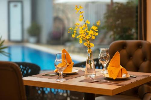 a wooden table with napkins and a vase with flowers at Tam Coc Holiday Hotel & Villa in Ninh Binh