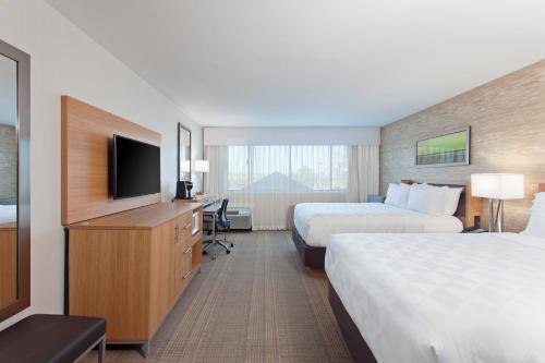 a hotel room with two beds and a flat screen tv at Holiday Inn Palmdale-Lancaster by IHG in Palmdale