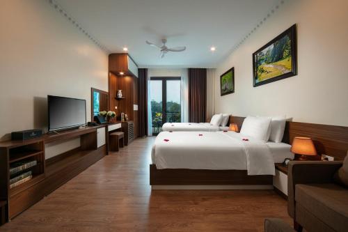 a bedroom with two beds and a flat screen tv at Tam Coc Holiday Hotel & Villa in Ninh Binh