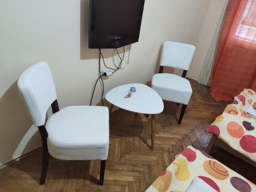 a room with three chairs and a table and a tv at Sweet Dream Rooms in Podgorica