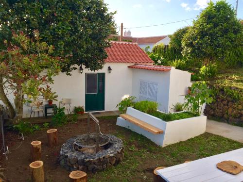 a small white house with a bench in a yard at The Azores Homestead - Terceira in Santa Bárbara