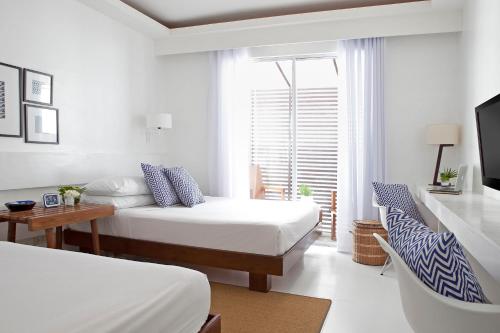 a bedroom with two beds and a desk and a tv at Blue Marina Boracay in Boracay