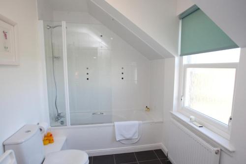 a white bathroom with a shower and a toilet at Killinallan Cottage in Port Charlotte