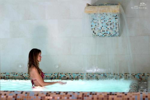 a woman is sitting in a swimming pool at Hotel Villa Durrueli Resort & Spa in Ischia