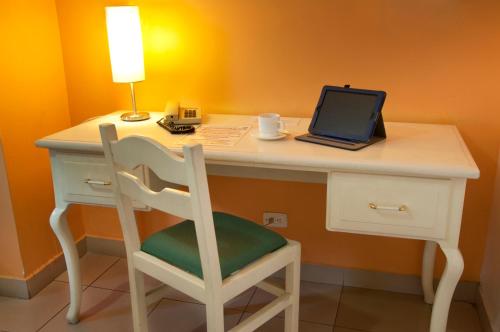 a desk with a laptop and a chair with a lamp at Hotel Sandmelis in Quito