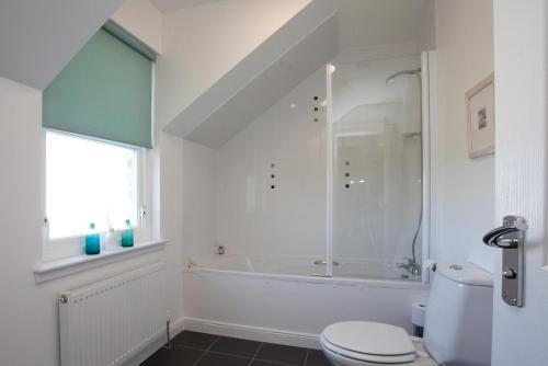 a bathroom with a shower and a toilet and a tub at Sanaigmore Cottage in Port Charlotte