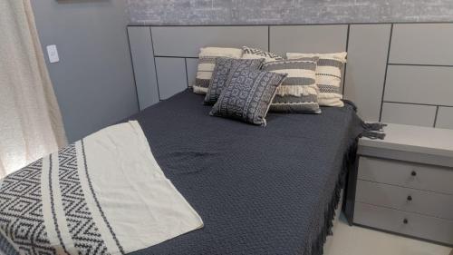 uma cama com almofadas num quarto em Edifício Panoramique 180 Graus, Cobertura no Guarujá