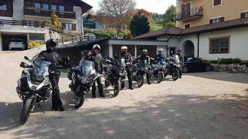 een groep mensen op motorfietsen geparkeerd buiten een huis bij Albergo GARNI' AURORA in Tret