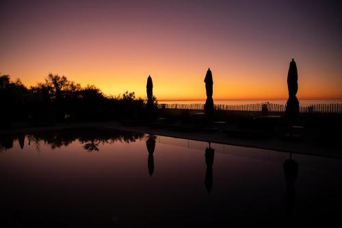 a sunset over a swimming pool with statues at Hôtel Plage Palace & Spa in Palavas-les-Flots