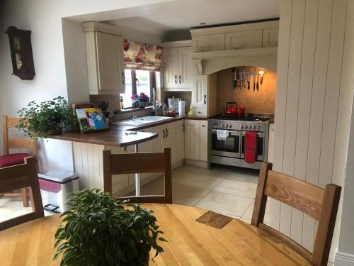 una cocina con armarios blancos y una mesa de madera con sidra de mesa en Beechtree House, en Dublín