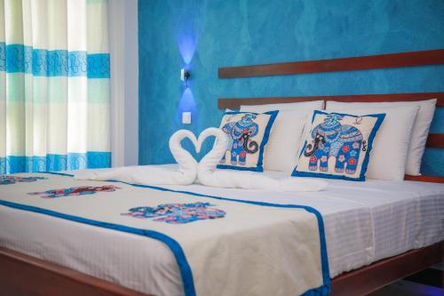 a bedroom with a white bed with a heart pillow at Blue Berry Villa in Hikkaduwa