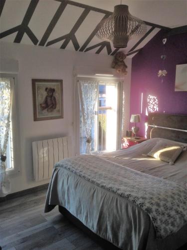 une chambre avec un grand lit aux murs violets dans l'établissement PERROT, à Villers-sur-Mer