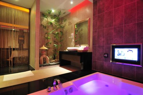 a bathroom with a purple tub with a tv in it at One + One Motel in Longtan