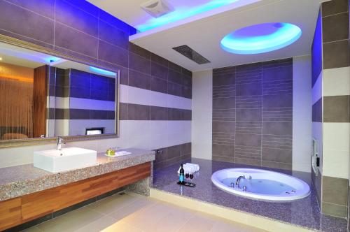 a bathroom with a tub and a sink and a mirror at One + One Motel in Longtan