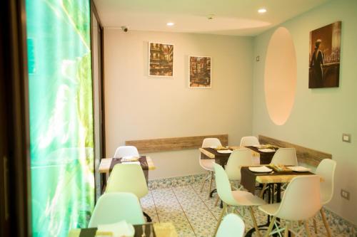 a dining room with tables and white chairs at Hotel Potenza in Naples