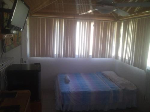 a bedroom with a bed and a window with curtains at Hostal Villas Mexico in San Juan del Sur