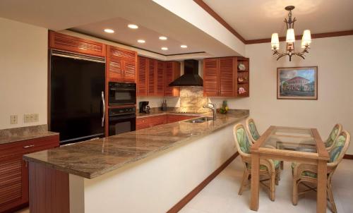 a kitchen with wooden cabinets and a table with chairs at Mauna Lani Point in Waikoloa