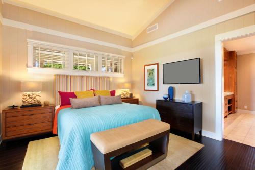 a bedroom with a bed and a flat screen tv at The Lodge at Kukuiula - CoralTree Residence Collection in Koloa