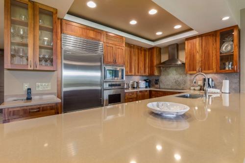 a kitchen with a stainless steel refrigerator and wooden cabinets at Mauna Lani Point in Waikoloa