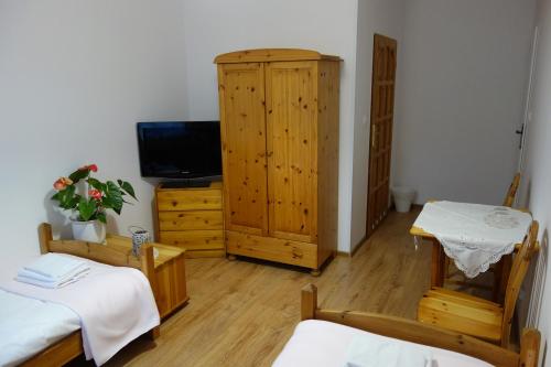 a room with two beds and a cabinet and a television at Dworek pod świerkami in Jelenia Góra