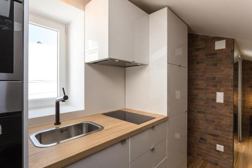 a kitchen with white cabinets and a sink and a window at LxFactory Apartment in Lisbon