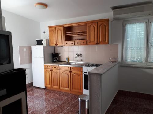 uma cozinha com armários de madeira e um frigorífico branco em Apartments Roviš em Tar