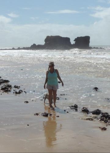 a woman walking on the beach with her dog at Casa na Praia com Piscina in Costa Dourada