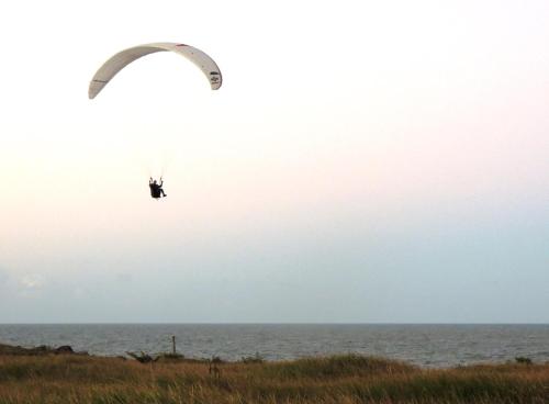 a paraglider is flying over the ocean at Casa na Praia com Piscina in Costa Dourada