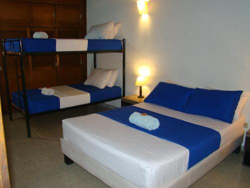 a bedroom with two beds with blue and white sheets at Yellow House Hostel in Medellín