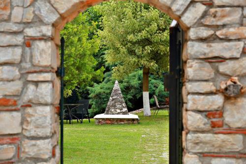 an opening in a stone wall with a tree in the grass at Hotel Nemesis in Stavroupoli