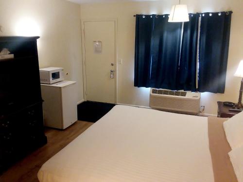 a bedroom with a bed and a window with a microwave at Walton Inn in Willard