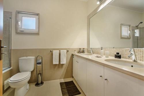 a bathroom with a toilet and a sink and a mirror at Formosa Apartment Cabanas Golf in Tavira