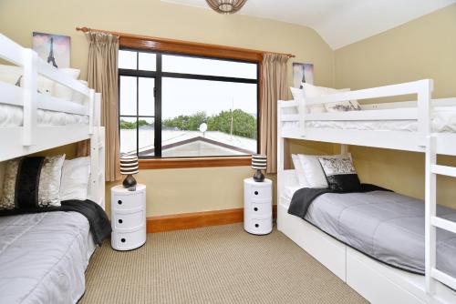two bunk beds in a room with a window at Racecourse Villa - Christchurch Holiday Home in Christchurch