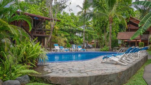 una piscina en un complejo con tumbonas azules y blancas en Hotel Los Ranchos, en Jacó