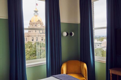 a bedroom with a window with a view of a building at The Drayton Hotel Savannah, Curio Collection by Hilton in Savannah
