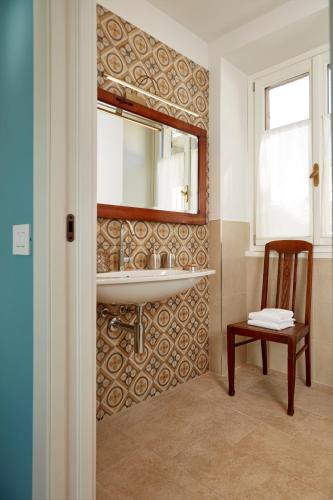 a bathroom with a sink and a mirror and a chair at Casa Svizzera Agriturismo in Barolo