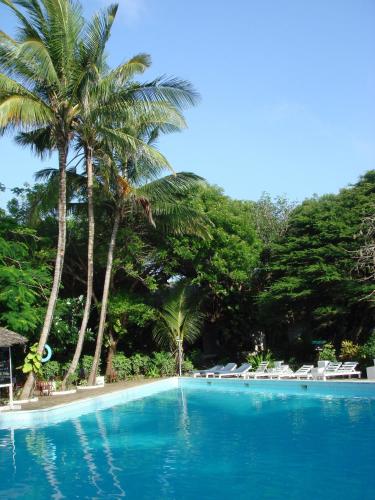 a swimming pool with palm trees and lounge chairs at Baobab Sea Lodge in Kilifi