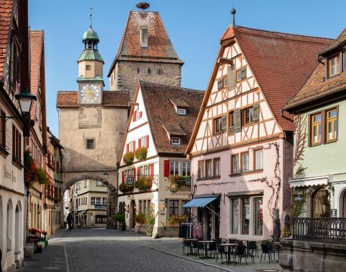 uma rua numa cidade medieval com uma torre de relógio em Romantik Hotel Markusturm em Rothenburg ob der Tauber