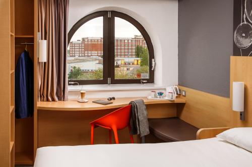 een kamer met een bureau, een bed en een raam bij ibis Southampton in Southampton