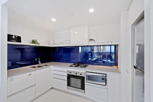 a white kitchen with white cabinets and a sink at Circle on Cavill - Gclr in Gold Coast