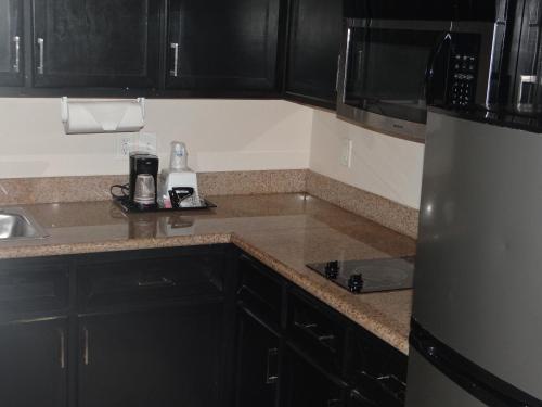 een keuken met zwarte kasten en een roestvrijstalen koelkast bij Regency Inn & Suites - Baytown in Baytown