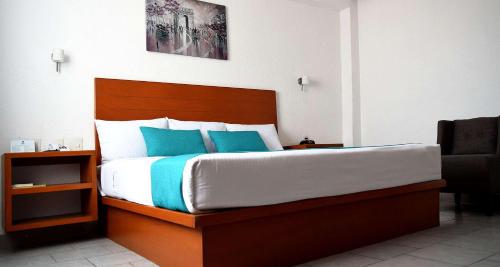 a bedroom with a large bed with blue pillows at Best Western Global Express in Veracruz