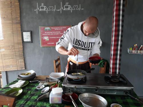 a man cooking food in a stove in a kitchen at One Homestay and Warung in Munduk
