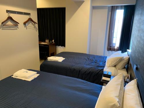 a hotel room with two beds and a desk at HOTEL LiVEMAX Tokyo Kanda EAST in Tokyo